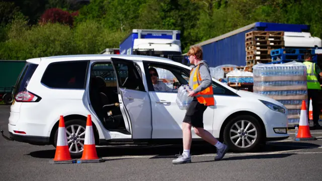 People loading water bottles into cars