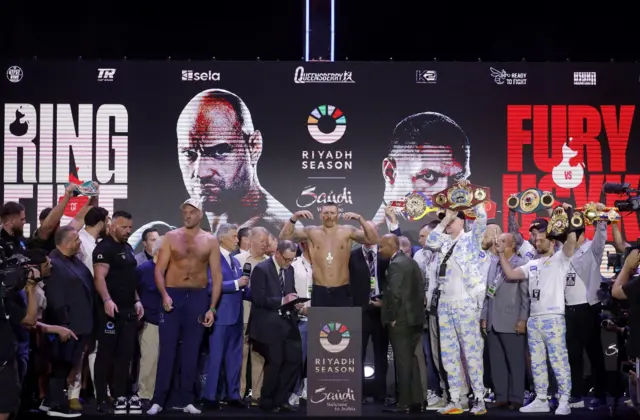 Oleksandr Usyk stand on the scales on a crowded stage