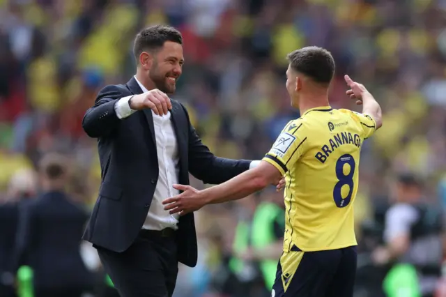 Des Buckingham, Manager of Oxford United, and Cameron Brannagan of Oxford United celebrate promotion to the Championship