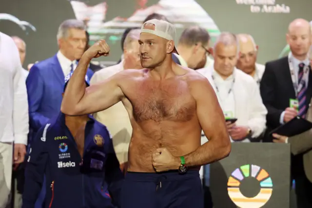 Tyson Fury holds up his arm as he stands shirtless