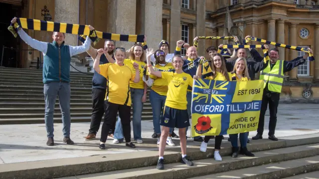 Blenheim Palace staff wearing yellow for Oxford United and holding Oxford United flags and scarves