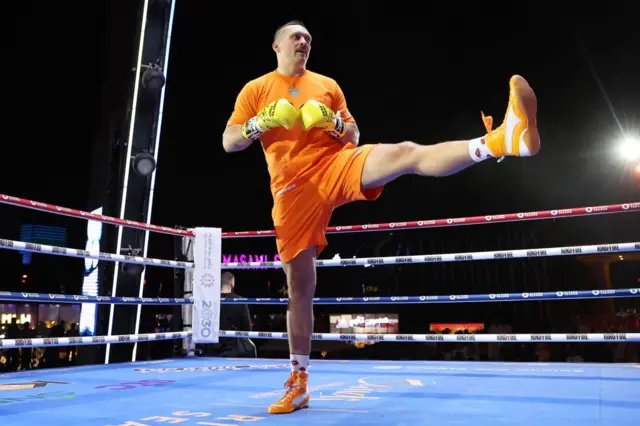 Oleksandr Usyk lifts up his leg to stretch in the ring