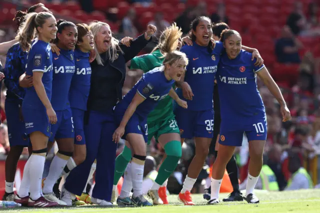 Chelsea's English manager Emma Hayes (C) and players react to their win on the touchline on the final whistle in the English Women's Super League football match between Manchester United and Chelsea at Old Trafford