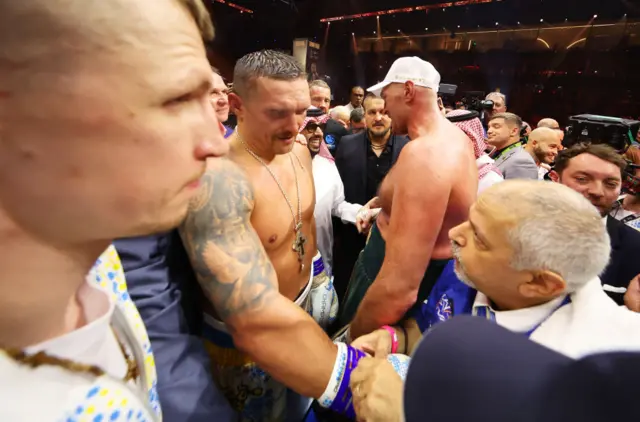 Oleksandr Usyk and Tyson Fury in the ring surrounded by people