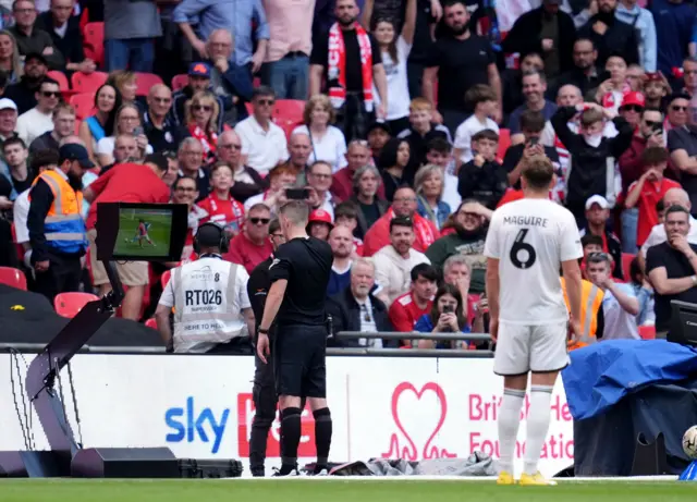 Referee Ben Toner looks at the VAR monitor