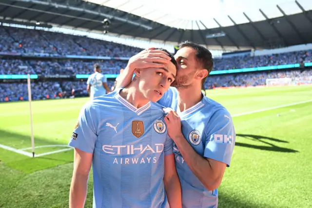 Phil Foden of Manchester City celebrates scoring his team's first goal as he is kissed by teammate Bernardo Silva during the Premier League match between Manchester City and West Ham United at Etihad Stadium