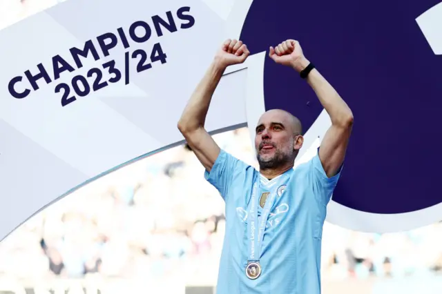 Pep Guardiola, Manager of Manchester City, celebrates with his Winners Medal as he acknowledges the fans from the Winners Podium after the Premier League match between Manchester City and West Ham United at Etihad Stadium