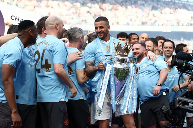 Kyle Walker of Manchester City looks on whilst holding alongside the backroom staff