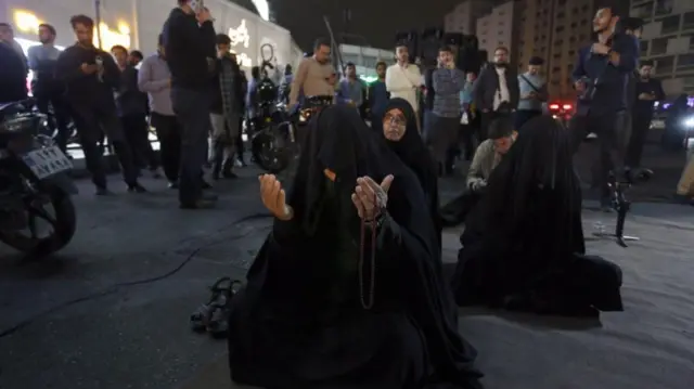 A woman holding her hands up in prayer for President Ebrahim Raisi on the streets of Tehran, Iran