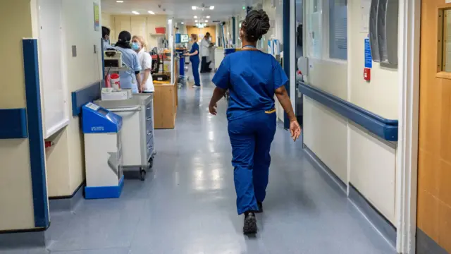 A member of staff walks through the corridor of an NHS hospital