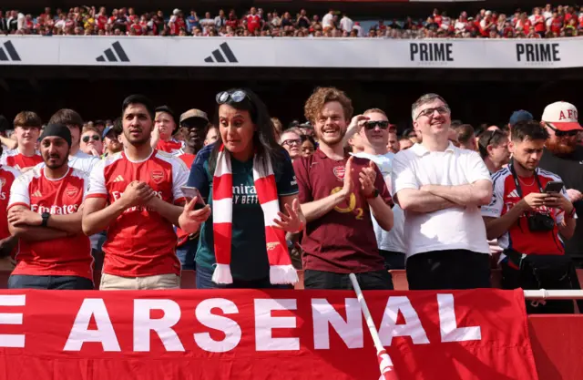 Arsenal fans check their phones for news from other games during the English Premier League football match between Arsenal and Everton at the Emirates Stadium