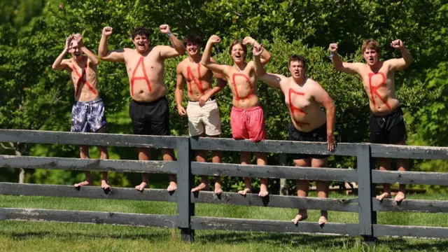 Six topless men with X A N D E R written on their chests