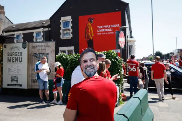 A Liverpool fan wearing a Jurgen Klopp mask looks at the mural of Jurgen Klopp outside Anfield during the Premier League match between Liverpool FC and Wolverhampton Wanderers at Anfield