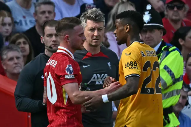 Wolverhampton Wanderers' Portuguese defender #22 Nelson Semedo (R) speaks with Liverpool's Argentinian midfielder #10 Alexis Mac Allister (L) as he leaves the pitch having been sent off during the English Premier League football match between Liverpool and Wolverhampton Wanderers at Anfield