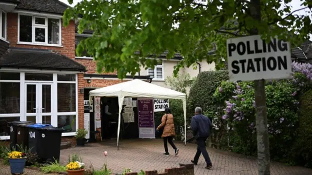 Voters walk towards a polling station at a garage inside a house during local elections in Croydo