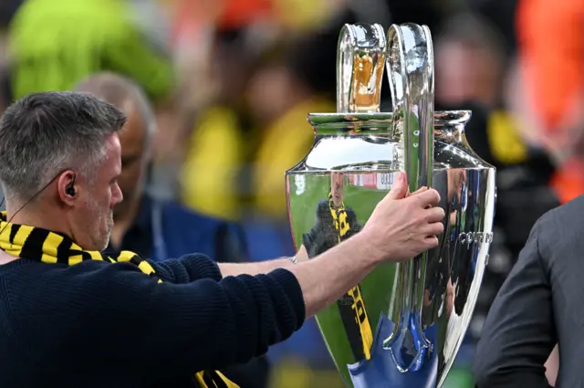 Jamie Carragher looks at the Champions League trophy at Borussia Dortmund v Paros St-Germain