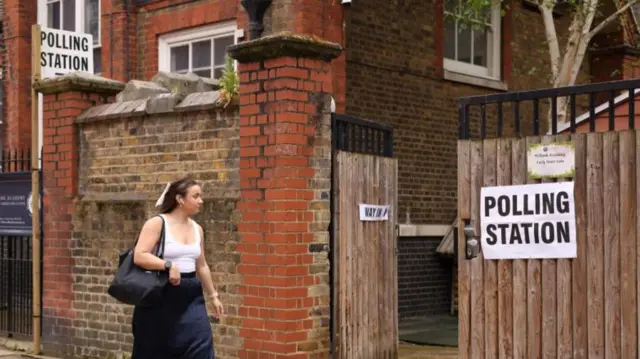 A woman walks past a polling station during local elections in London, Britain May 2, 2024.