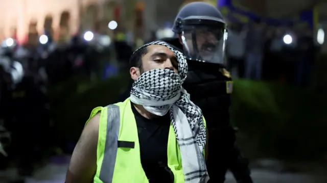 A helmeted officer detains a pro-Palestinian protester.