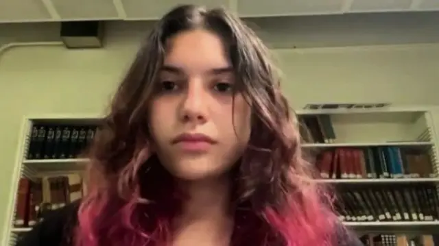 Kenza, a student at UCLA, in front of a bookshelf