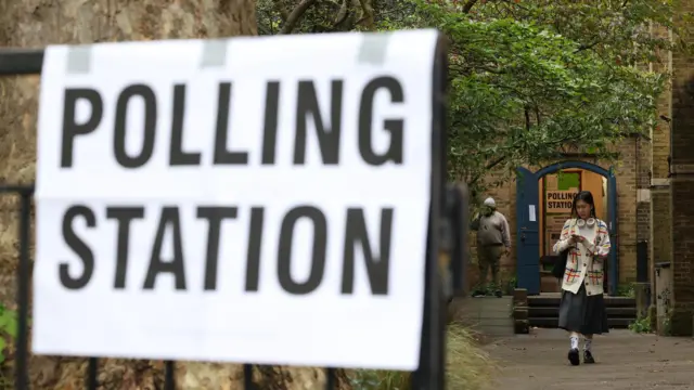 A woman leaves a polling station during local elections in London