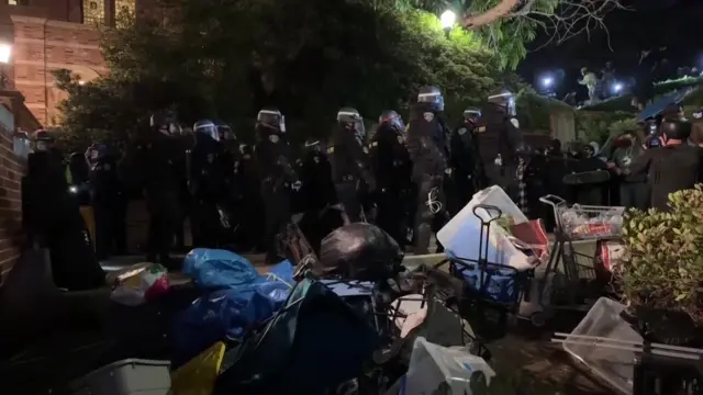 Police officers are seen clearing through and walking into the encampment