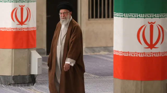 Iran's supreme leader Ayatollah Khamenei stands between two pillars that have two Iranian flags draped round them