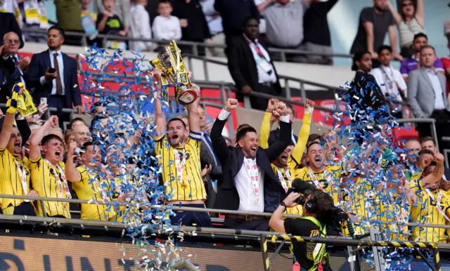 Oxford United's Elliott Moore cheers and triumphantly lifts the trophy after the Sky Bet League One play-off final at Wembley Stadium, as ticker tape erupts