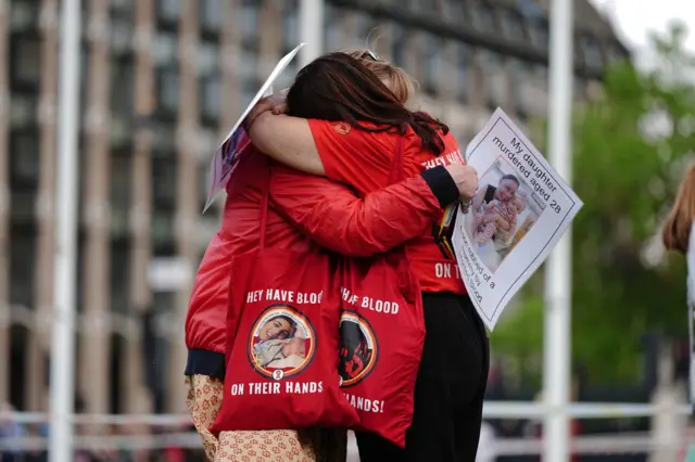 Two infected blood activists embrace each other