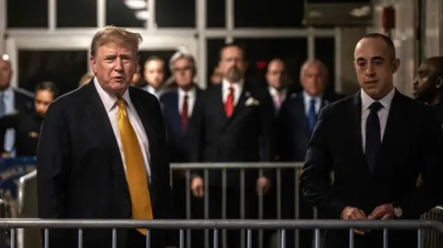 Donald Trump speaking outside court with his supporters behind him and lawyer Emil Bove standing next to him.