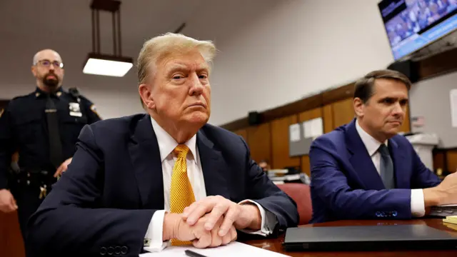 Donald Trump sits with hands on desk at court