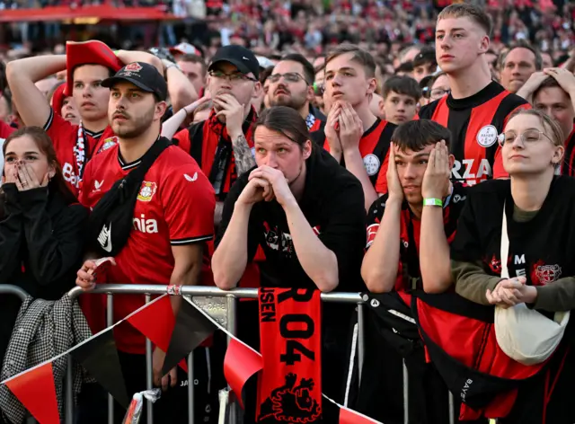 Leverkusen fans stand glumly back home at a screening