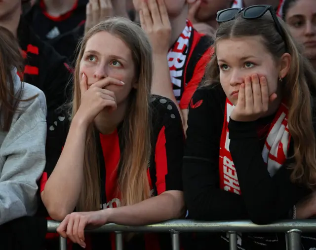 Leverkusen fans stand glumly back home at a screening