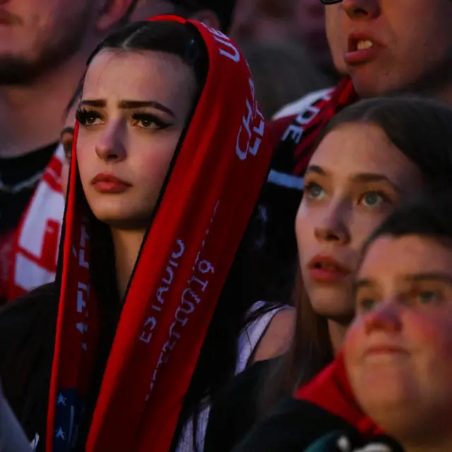 A Leverkusen fan watches on with her scarf around her head