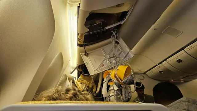 Oxygen masks are seen hanging from the ceiling of the Singapore-London flight