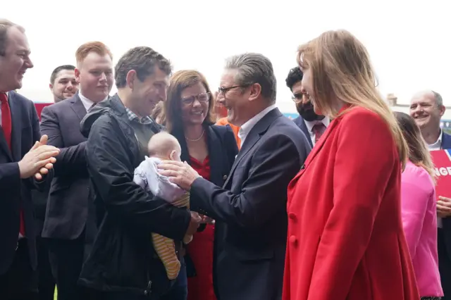 Labour Party leader Sir Keir Starmer meets a baby during a visit to Gillingham Football club in Gillingham, Kent