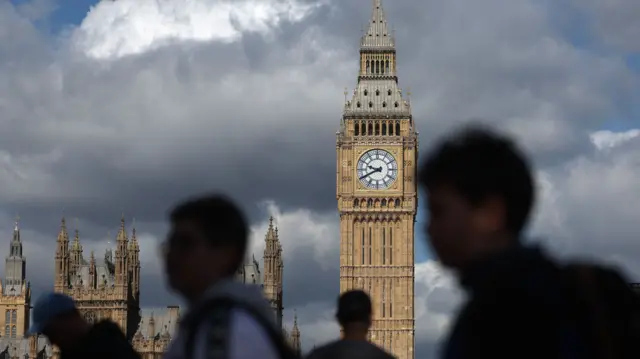 Image of the houses of Parliament with blurred people walking past in the foreground.