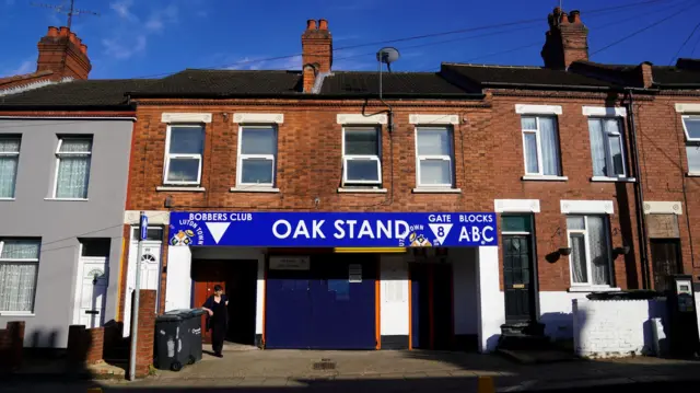 Entrance to Luton Town Football Club between terraced houses with a sign above saying Oak Stand