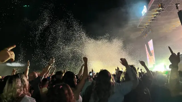 Confetti blows in the night across the main stage