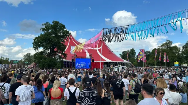 A crowd gathers to watch Cat Burns outside a big tent