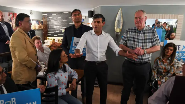 Rishi Sunak standing near Bob Blackman and speaking to attendees at the campaign event.