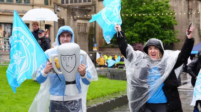 Manchester City fans with a blow-up trophy and flags