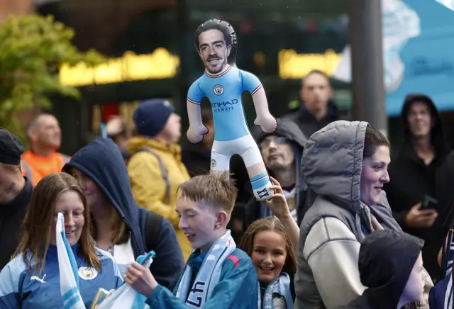 fans, with one holding a Jack Grealish doll