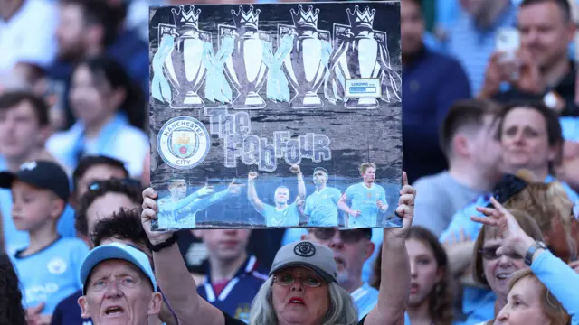 A Manchester City fan displays a banner in the stand