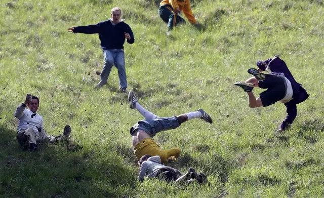 Contestants in mid air falling down Cooper's Hill as part of the cheese rolling races