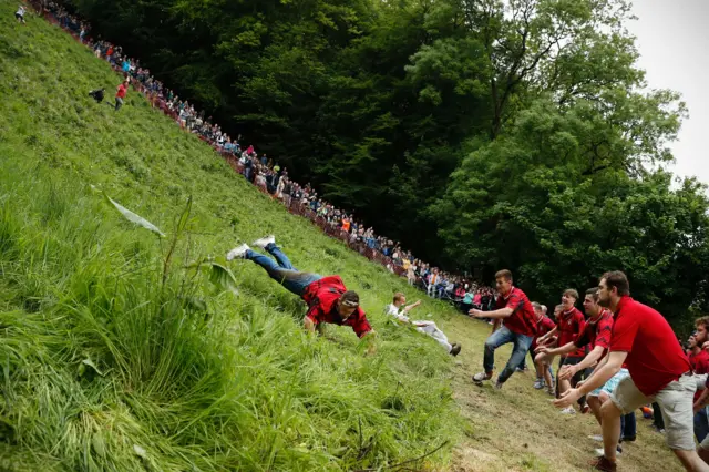 Cheese rolling contestants are stopped by volunteers at the bottom of Cooper's Hill