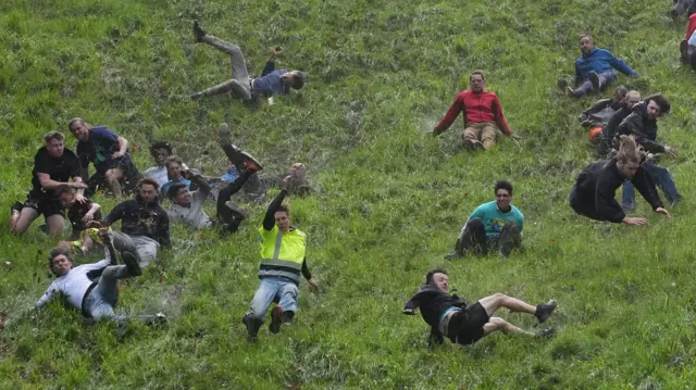 Competitors in the cheese rolling slide down Cooper's Hill in one of the men's races