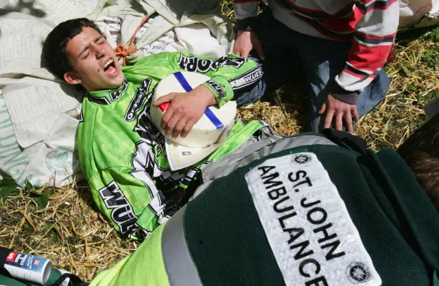 A cheese rolling competitor is treated by medical staff at the foot of Cooper's Hill in Gloucestershire