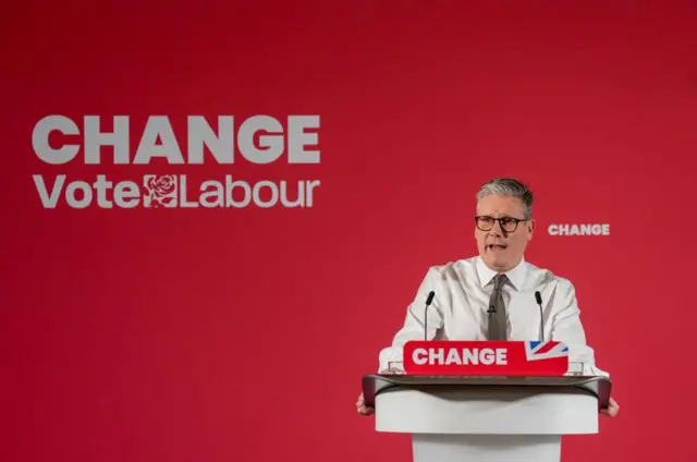 Keir Starmer speaks at a podium in front of a red background adorned with Labour's 2024 election motto "change"