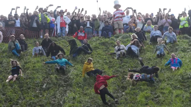 Competitors from the women's race roll down the hill