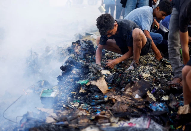 Palestinians search for food among burnt debris in the aftermath of Sunday's strike on Rafah